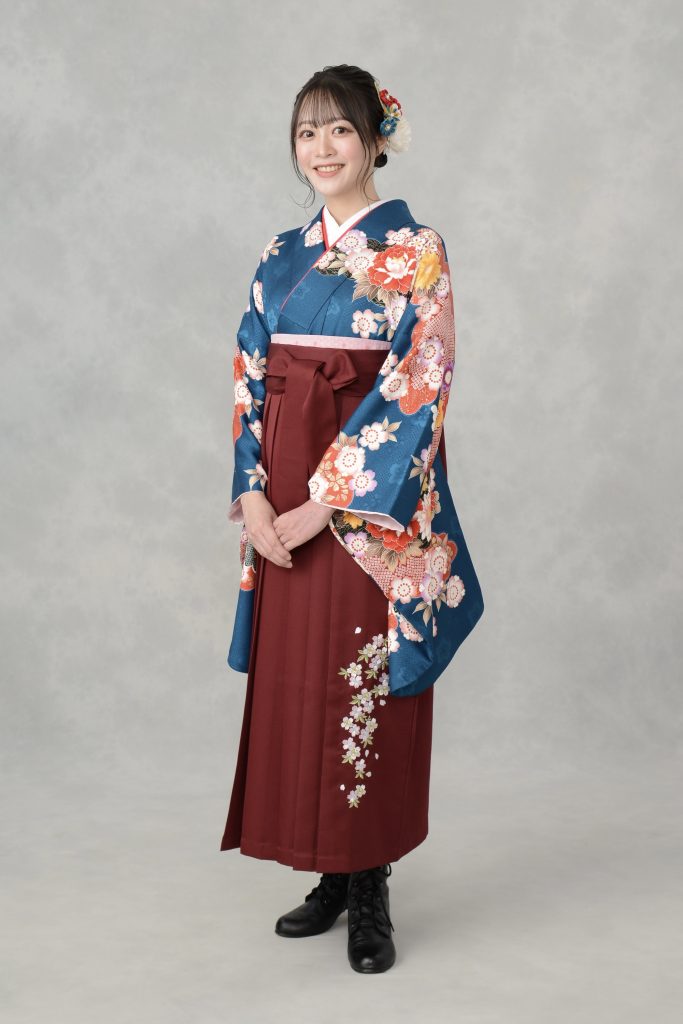 キモノモード町田店の卒業袴のスタジオ写真。青い袴用の二尺袖着物に、えんじ色の袴のコーディネート。桜の刺繍袴。