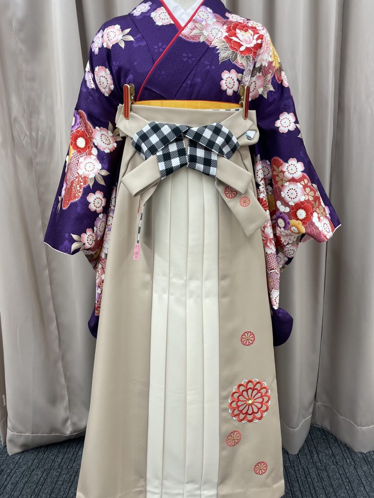 紫の着物にベージュ・クリームの袴を合わせた袴姿